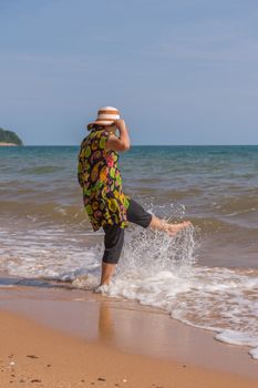 Asia woman plump body in colorful dress with hat posing at beach with blue sea and sky when travel