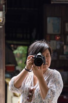 Asia woman plump body in colorful dress take a photo by her camera at old town when travel