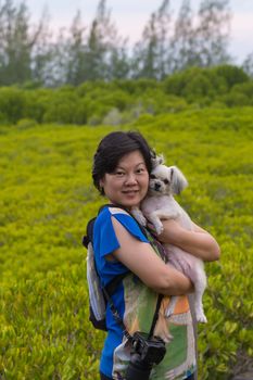 Asia woman plump body in colorful dress and her dog posing at Mangrove forrest or Golden Meadow (Thung Prong Thong in Thai language) is a nalure travel point at Rayong, Thailand