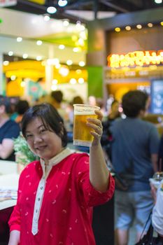 Asia woman plump body have fun holding a beer in pub with indoor party , process in soft orange sun light style