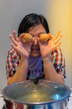 Asia woman plump body cooking food by put a flesh egg in to a hot pot for make a sukiyaki or shabu , process in soft orange sun light style