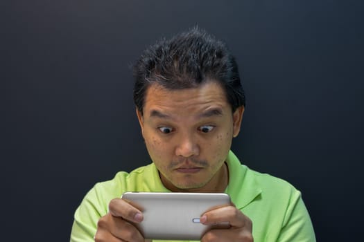Asia man dazed and shock using smartphone on black background
