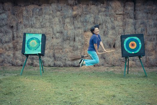 Asia woman plump body is a witch riding a broom flying to archer target , process in vintage style