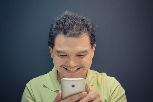 Asia man happy and smiling using smartphone on black background , process in vintage style