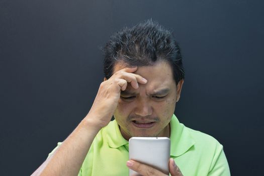 Asia man confused and worried using smartphone on black background