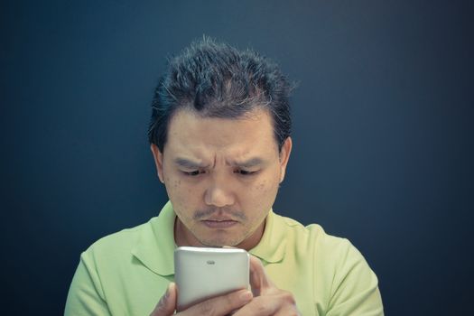 Asia man confused and worried using smartphone on black background , process in vintage style