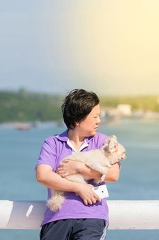 Asia woman plump body and her dog standing at estuary (river side and sea) when travel , process in soft orange sun light style
