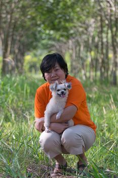 Asia woman plump body and her dog at rubber tree in row at a rubber tree plantation natural latex.