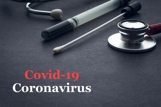 COVID-19 or CORONAVIRUS text with stethoscope and medical swab on black background. Covid-19 or Coronavirus concept. 