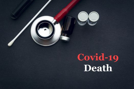 COVID-19 or CORONAVIRUS DEATH text with stethoscope, medical swab and vial on black background. Covid-19 or Coronavirus concept. 