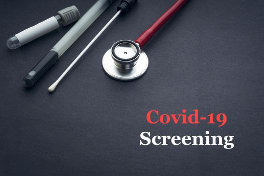 COVID-19 or CORONAVIRUS SCREENING text with stethoscope, medical swab and blood sample tube on black background. Covid-19 or Coronavirus concept. 