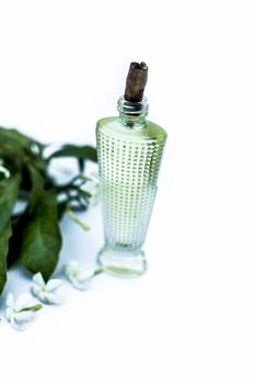 Close up of spray or perfume of Indian jasmine flower or juhi or Jasminum Auriculatum isolated on white in a small bottle with raw flowers.