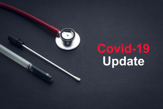 COVID-19 or CORONAVIRUS UPDATE text with stethoscope and medical swab on black background. Covid-19 or Coronavirus concept. 