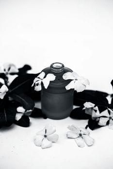 White colored flowers along with leaves and essential herbal detoxifying oil in a glass bottle isolated on white.