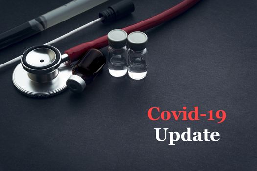 COVID-19 or CORONAVIRUS UPDATE text with stethoscope, medical swab and vial on black background. Covid-19 or Coronavirus concept. 