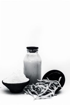 Popular Indian &amp; Asian ayurvedic herb isolated on white in a clay bowl i.e. Musli or safed musli or Chlorophytum borivilianum with its powder in a clay bowl and raw milk in a transparent glass bottle.