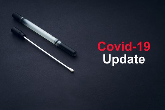 COVID-19 or CORONAVIRUS UPDATE text with medical swab on black background. Covid-19 or Coronavirus concept. 