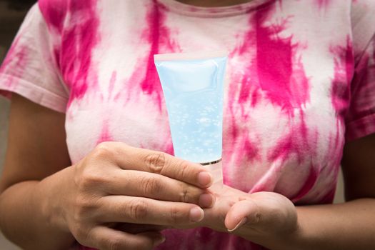 Woman wearing tie-dye clothes, holding one tube of alcohol gel