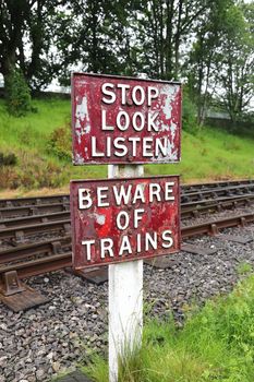 A sign warning pedestrians to stop, look and listen and beware of oncoming trains before they cross the railway line.