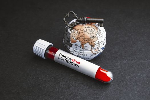 CORONAVIRUS LOCKDOWN text with world globe, key and Blood test vacuum tube on black background. Covid-19 or Coronavirus Concept 