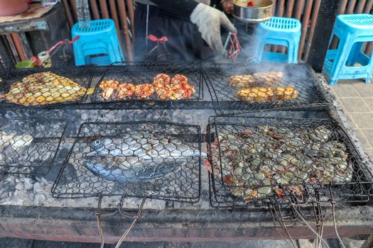 Fish barbecue. Cooking BBQ seafood on fire. Grill with burning coals. barbecue in excellent warung at the fish market on tropical Bali island in Jimbaran. Fresh, healthy and delicious seafood.