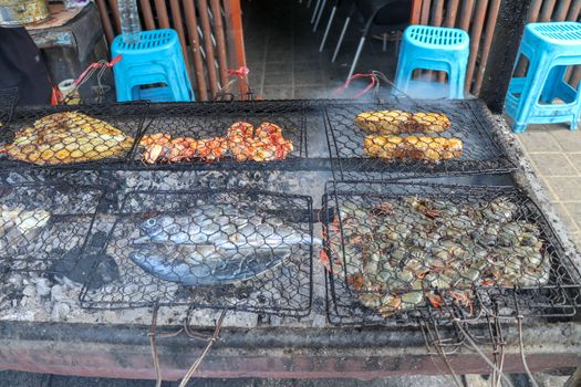 Fish barbecue. Cooking BBQ seafood on fire. Grill with burning coals. barbecue in excellent warung at the fish market on tropical Bali island in Jimbaran. Fresh, healthy and delicious seafood.