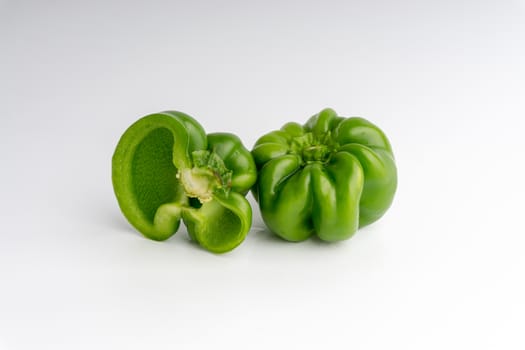 Fresh green bell peppers (capsicum) on a white background. Selective focus and crop fragment