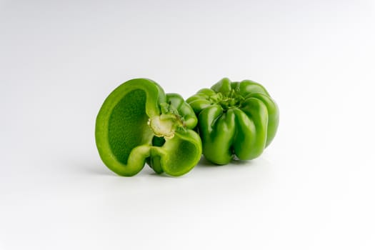 Fresh green bell peppers (capsicum) on a white background. Selective focus and crop fragment