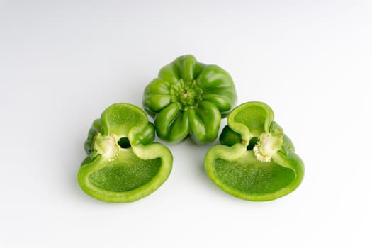 Fresh green bell peppers (capsicum) on a white background. Selective focus and crop fragment