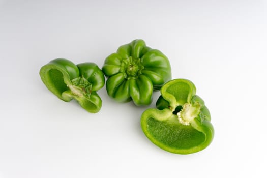 Fresh green bell peppers (capsicum) on a white background. Selective focus and crop fragment