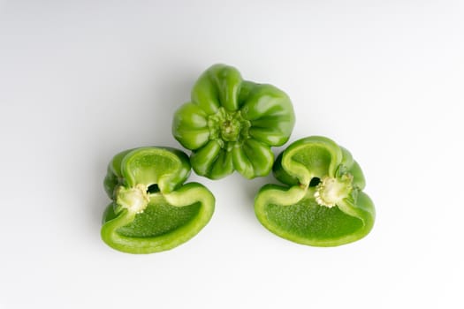 Fresh green bell peppers (capsicum) on a white background. Selective focus and crop fragment