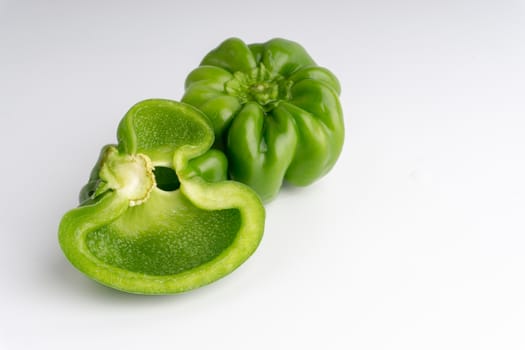 Fresh green bell peppers (capsicum) on a white background. Selective focus and crop fragment