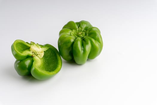 Fresh green bell peppers (capsicum) on a white background. Selective focus and crop fragment