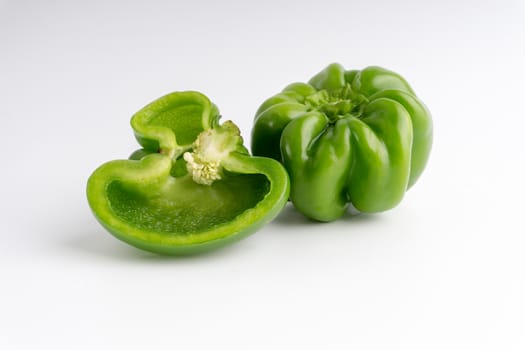 Fresh green bell peppers (capsicum) on a white background. Selective focus and crop fragment