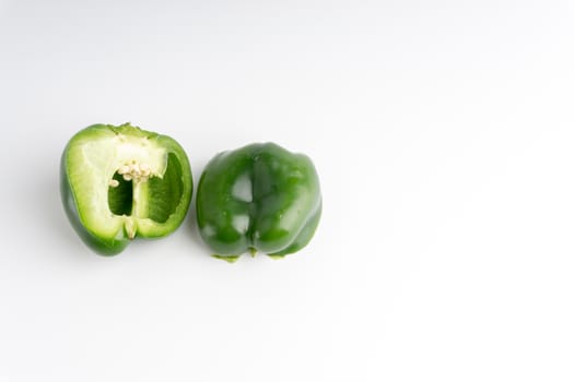 Fresh green bell peppers (capsicum) on a white background. Selective focus and crop fragment