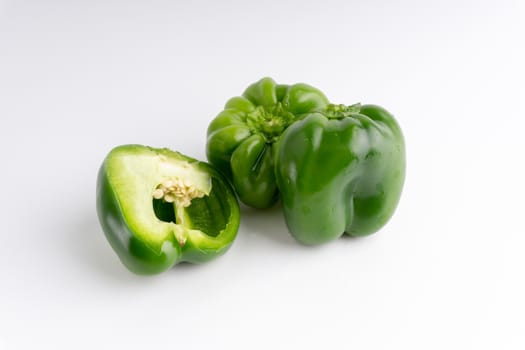 Fresh green bell peppers (capsicum) on a white background. Selective focus and crop fragment