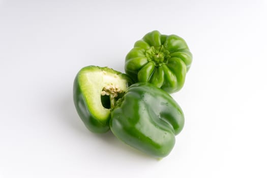 Fresh green bell peppers (capsicum) on a white background. Selective focus and crop fragment