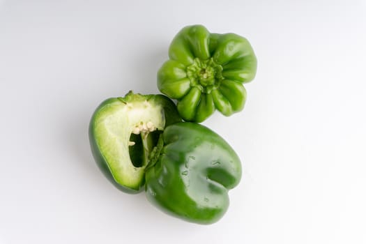 Fresh green bell peppers (capsicum) on a white background. Selective focus and crop fragment