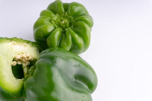 Fresh green bell peppers (capsicum) on a white background. Selective focus and crop fragment