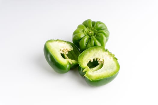 Fresh green bell peppers (capsicum) on a white background. Selective focus and crop fragment