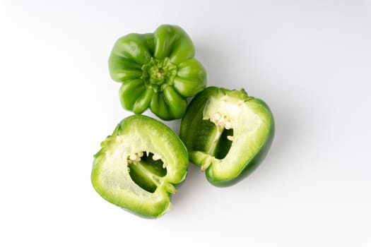 Fresh green bell peppers (capsicum) on a white background. Selective focus and crop fragment