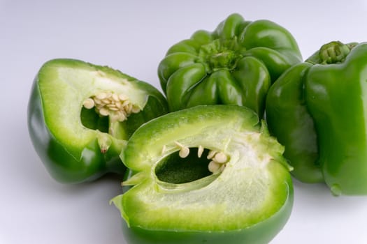 Fresh green bell peppers (capsicum) on a white background. Selective focus and crop fragment