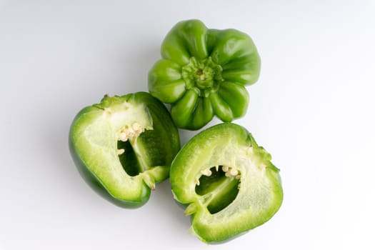 Fresh green bell peppers (capsicum) on a white background. Selective focus and crop fragment