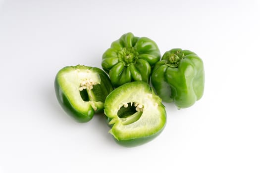 Fresh green bell peppers (capsicum) on a white background. Selective focus and crop fragment