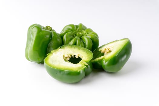 Fresh green bell peppers (capsicum) on a white background. Selective focus and crop fragment