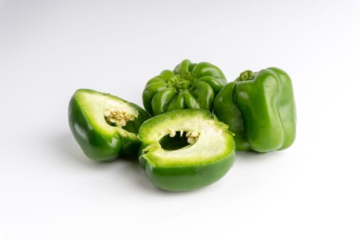 Fresh green bell peppers (capsicum) on a white background. Selective focus and crop fragment