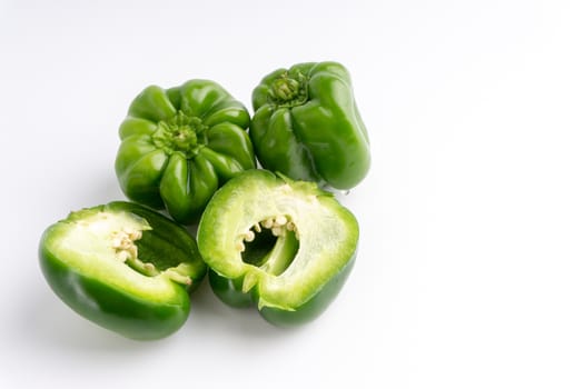 Fresh green bell peppers (capsicum) on a white background. Selective focus and crop fragment