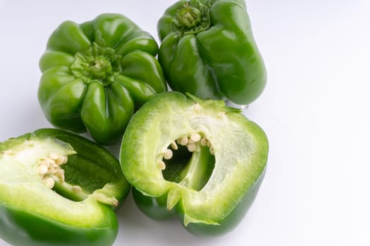 Fresh green bell peppers (capsicum) on a white background. Selective focus and crop fragment