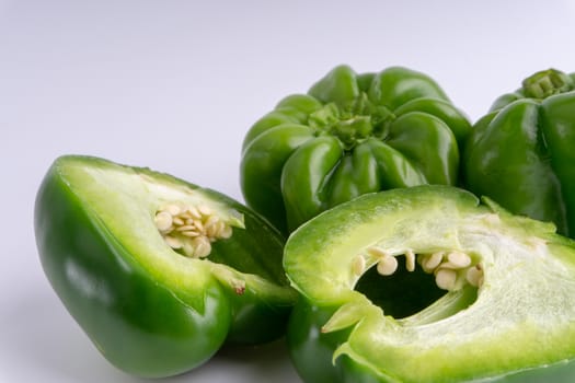 Fresh green bell peppers (capsicum) on a white background. Selective focus and crop fragment