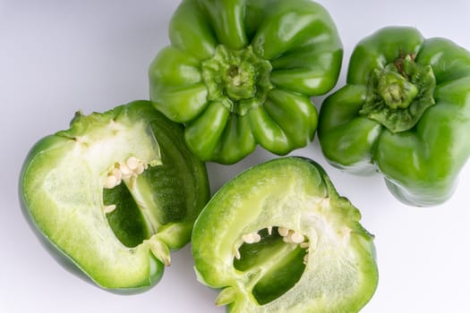 Fresh green bell peppers (capsicum) on a white background. Selective focus and crop fragment